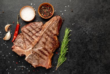 Baharatlı ızgara biftek ve siyah arka planda otlar.