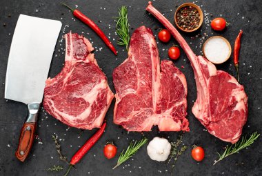 Siyah arka planda baharatlı ve sebzeli çiğ biftek.