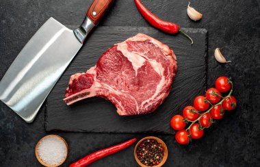 Baharatlı, otlu çiğ et ve siyah arka planda pişirmek için malzemeler. en üstteki görünüm.