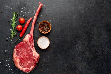 Siyah arka planda baharatlı ve sebzeli çiğ biftek.