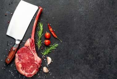 Siyah arka planda baharatlı ve sebzeli çiğ biftek.