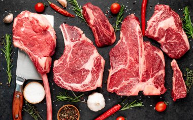 Siyah arka planda baharatlı ve sebzeli çiğ biftek.