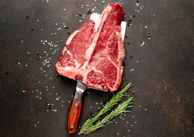 Biberiyeli çiğ biftek ve siyah masada baharatlar.