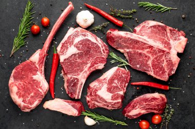 Siyah arka planda baharatlı ve sebzeli çiğ biftek.