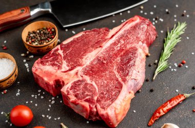 Biberiyeli çiğ biftek ve siyah masada domates.