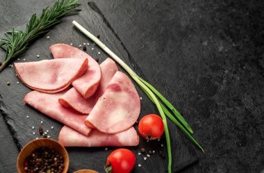 Baharatlı domuz jambonu ve siyah arka planda otlar.