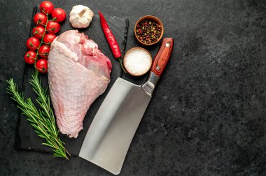 Baharatlı çiğ hindi budu ve siyah arka planda otlar. Üst Manzara. Metnin için boş yer.