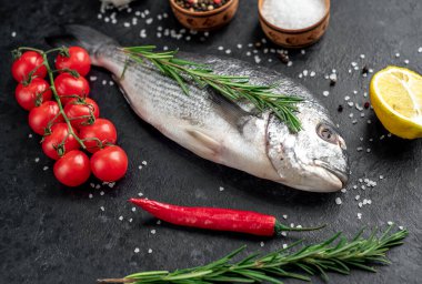 Limonlu çiğ dorado balığı ve siyah arka planda baharat.