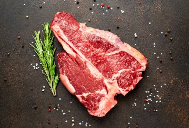 Biberiyeli çiğ biftek ve siyah masada baharatlar.