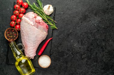 Baharatlı çiğ hindi budu ve siyah arka planda otlar. Üst Manzara. Metnin için boş yer.