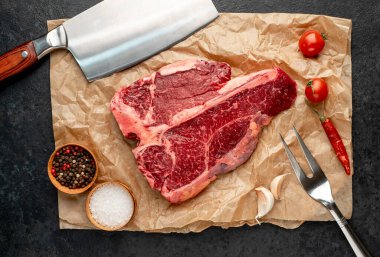 Baharatlı çiğ biftek ve ahşap arka planda otlar.