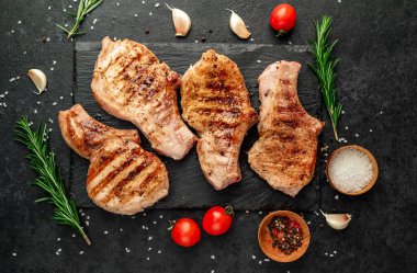 Baharatlı ızgara et ve siyah arka planda otlar.