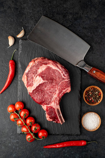 raw beef with vegetables and spices on wooden background