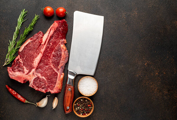 raw beef steak with spices and herbs on black background