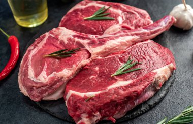 Biberiyeli çiğ et ve siyah arka planda bitkiler. 