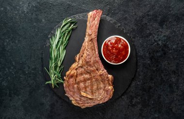 Baharatlı ızgara et ve siyah arka planda otlar. 