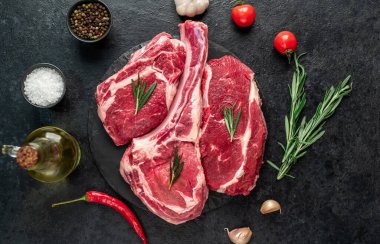 Biberiyeli çiğ et ve siyah arka planda bitkiler. 