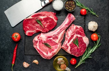 Biberiyeli çiğ et ve siyah arka planda bitkiler. 