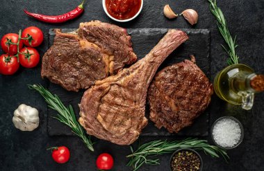 Baharatlı ızgara et ve siyah arka planda otlar. 