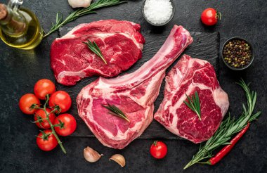 Biberiyeli çiğ et ve siyah arka planda bitkiler. 