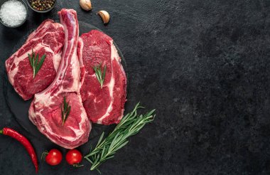 Biberiyeli çiğ et ve siyah arka planda bitkiler. 