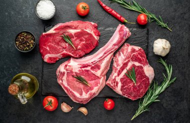 Biberiyeli çiğ et ve siyah arka planda bitkiler. 