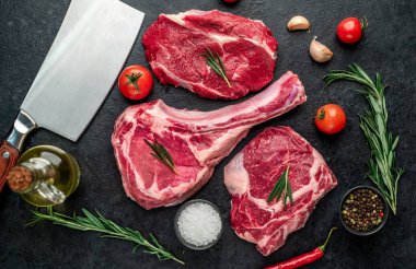 Biberiyeli çiğ et ve siyah arka planda bitkiler. 