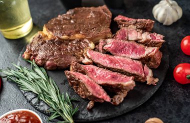 Baharatlı ızgara et ve siyah arka planda otlar. 