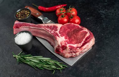 Biberiyeli çiğ et ve siyah arka planda bitkiler. 