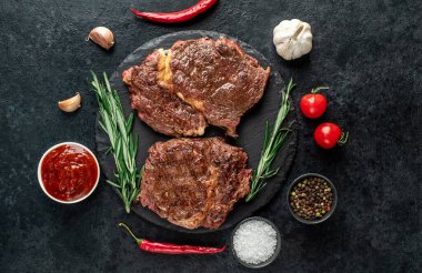 Baharatlı ızgara et ve siyah arka planda otlar. 