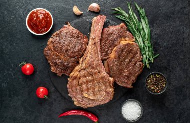 Baharatlı ızgara et ve siyah arka planda otlar. 