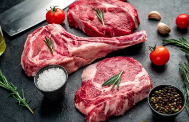 Biberiyeli çiğ et ve siyah arka planda bitkiler. 