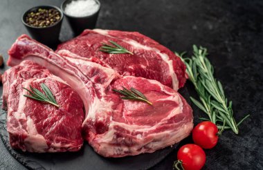 Biberiyeli çiğ et ve siyah arka planda bitkiler. 