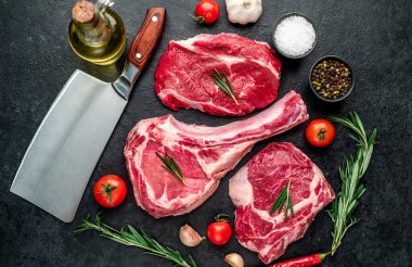 Biberiyeli çiğ et ve siyah arka planda bitkiler. 