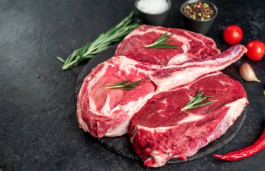 Biberiyeli çiğ et ve siyah arka planda bitkiler. 