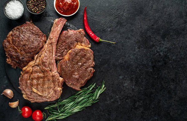 grilled meat with spices and herbs on black background 