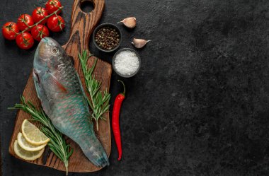 Siyah zemin üzerinde limonlu çiğ balık ve biberiye.