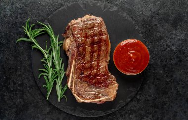 Baharatlı ızgara biftek ve siyah arka planda otlar.