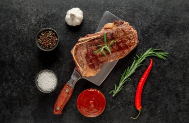 Baharatlı ızgara biftek ve siyah arka planda otlar.