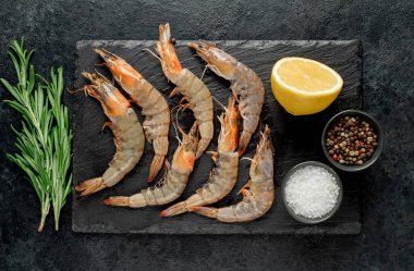 Siyah arka planda limonlu ve biberiyeli çiğ taze karides. en üstteki görünüm.