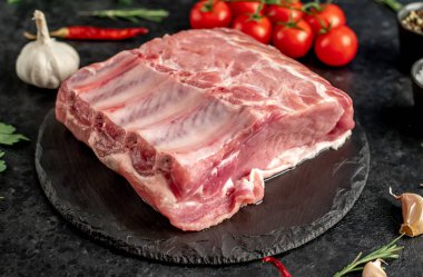 Baharatlı çiğ biftek ve siyah arka planda otlar.