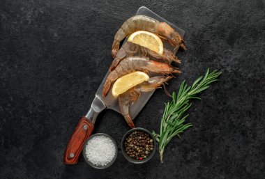 Siyah arka planda limonlu ve biberiyeli çiğ taze karides. en üstteki görünüm.