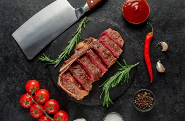 Baharatlı ızgara biftek ve siyah arka planda otlar.