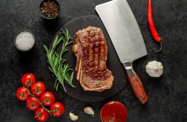 Baharatlı ızgara biftek ve siyah arka planda otlar.