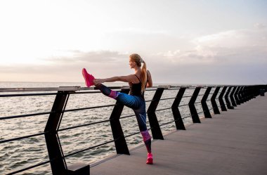 Genç bir kadın şafak vakti okyanus manzaralı sette yoga yapıyor..