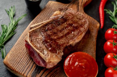 Baharatlı ızgara biftek ve siyah arka planda otlar.