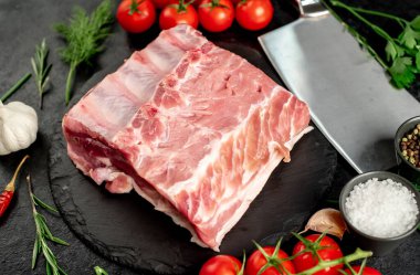 Baharatlı çiğ biftek ve siyah arka planda otlar.