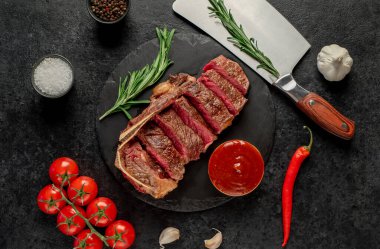 Baharatlı ızgara biftek ve siyah arka planda otlar.