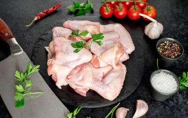 Siyah arka planda baharatlı ve otlu çiğ tavuk kanatları.