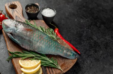 Siyah zemin üzerinde limonlu çiğ balık ve biberiye.